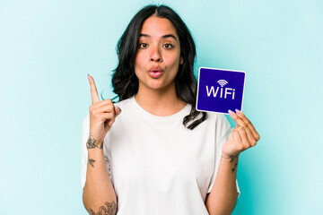 Young hispanic woman holding wifi placard isolated on yellow background having some great idea, concept of creativity.