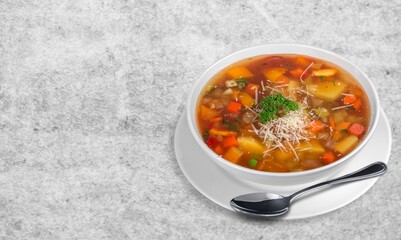 Tasty clear soup with beef slices and vegetables. Served in bowl on desk