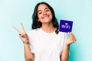 Young hispanic woman holding wifi placard isolated on yellow background joyful and carefree showing...
