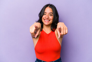 Young hispanic woman isolated on purple background cheerful smiles pointing to front.