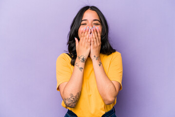 Young hispanic woman isolated on purple background laughing about something, covering mouth with...