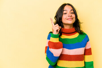 Young hispanic woman isolated on yellow background showing number one with finger.