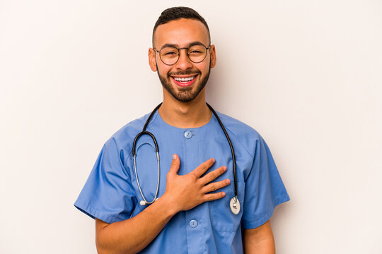 Young Hispanic Nurse Man Isolated On White Background Laughs Out Loudly Keeping Hand On Chest.