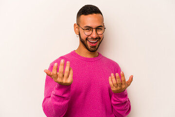 Naklejka premium Young hispanic man isolated on white background pointing with finger at you as if inviting come closer.
