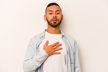 Young hispanic man isolated on white background taking an oath, putting hand on chest.