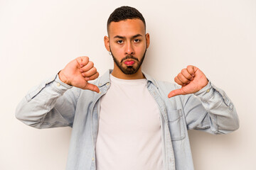 Young hispanic man isolated on white background showing a dislike gesture, thumbs down....