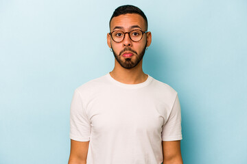 Young hispanic man isolated on blue background sad, serious face, feeling miserable and displeased.