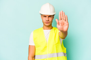 Young laborer caucasian man isolated on blue background standing with outstretched hand showing...