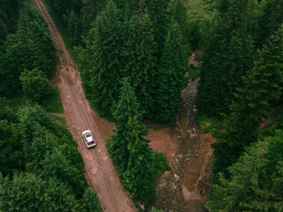 aerial view of suv car on trail road in forest