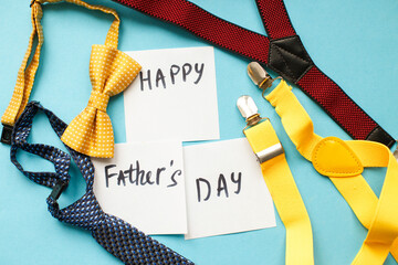 men's ties, suspenders and bow ties on blue background with copy space. father's day concept