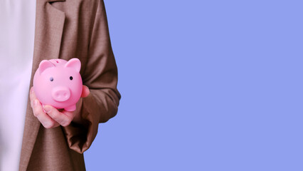 Woman teacher holding a piggy bank in her hands on a blue background, banner close-up