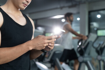 Fototapeta na wymiar Hands of man use smartphone in fitness during work out