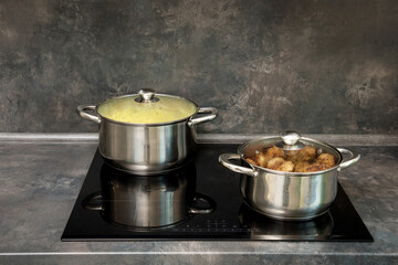 pots with cutlets and boiled potatoes on the induction stove
