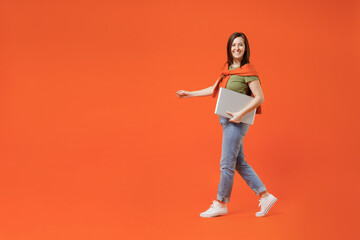 Fototapeta na wymiar Full body side view young excited happy fun woman 20s wear khaki t-shirt tied sweater on shoulders hold use work on laptop pc computer look aside isolated on plain orange background studio portrait
