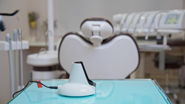 A dentist's assistant in black gloves shows how to work properly with a polymerization lamp in a medical office. A lesson for dentists and their assistants.