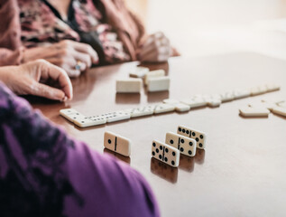 close-up of two elderly people playing dominoes. unrecognizable people. concept of fun and old age....