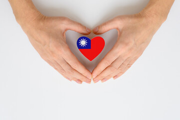 The national flag of Taiwan (Republic of China) in female hands. The concept of patriotism, respect and solidarity with the citizens of Taiwan.