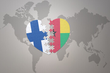 puzzle heart with the national flag of guinea bissau and finland on a world map background. Concept.