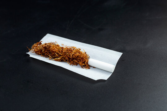 Rolling tobacco with filter tip and paper, isolated on black background