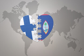 puzzle heart with the national flag of guam and finland on a world map background. Concept.