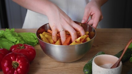 Close-up of a woman preparing vegetables in the kitchen. The hands of an unrecognizable woman stir vegetables in a plate with a spoon. Cooking in the kitchen