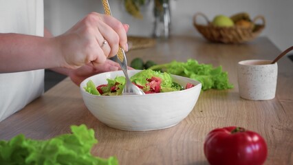Close-up of an unrecognizable woman's hand preparing a salad. Cooking in the kitchen.