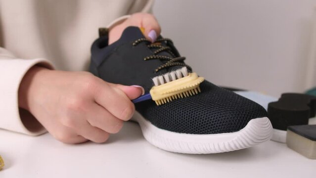Cleaning a sneaker with a shoe care brush. close-up slow motion