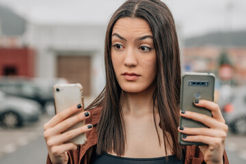 girl looking at mobile phones with an expression of doubt or surprise - obrazy, fototapety, plakaty