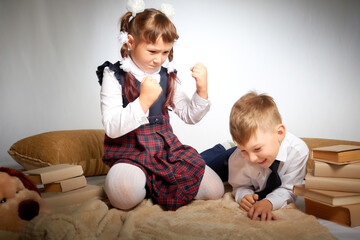 A schoolboy and schoolgirl in uniform having fight, argument, fun and rest in the room. A boy and girl during fun photo shoot about school. September 1 holiday in Russia