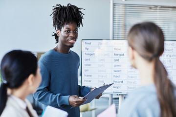 Portrait of black young man in group discussion during English seminar in office setting