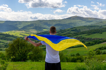 A boy with a flag of Ukraine in the mountains - obrazy, fototapety, plakaty
