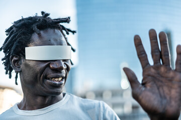 African gamer man using futuristic augmented reality glasses outdoor with city background