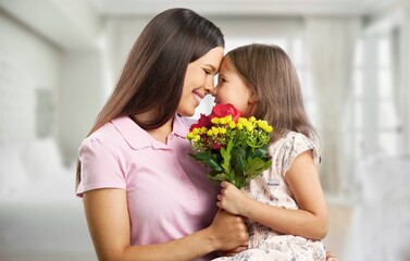 Fototapeta na wymiar Little daughter congratulating mom with Mother's day at home and giving her fresh flower bouquet