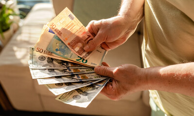Senior woman holding money americain dollars and euro in hands. Savings from pension. planning...