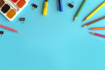 Many stationary supplies on blue background with space for text. Office accessories flat lay. First September, back to school, education, creativity concept. Pens, pencils and paints with copyspace 