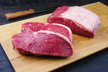 Rohes dry aged Wagyu Roastbeef Steak angeboten als close-up auf einem Design Holz Board