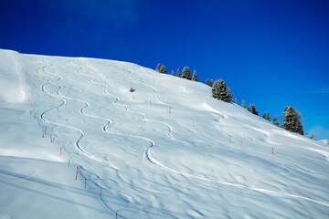 Traces from off-piste snowboarding on a mountain over blue sky