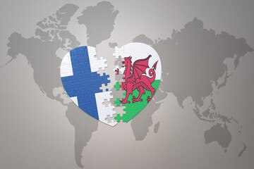 puzzle heart with the national flag of wales and finland on a world map background. Concept.