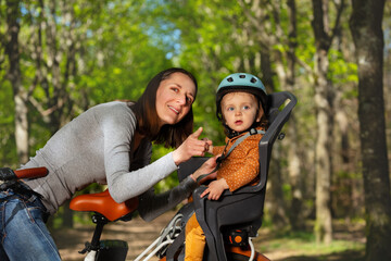 Fototapeta premium Woman play with child sitting in electric bike pointing finger