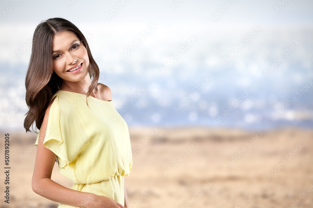 Sticker Portrait of young woman at sea looking at camera. Smiling girl standing at the beach