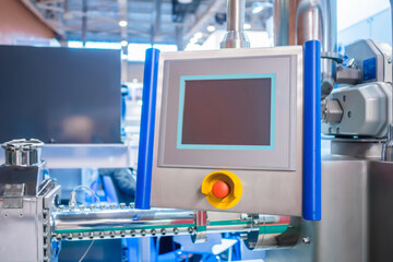 Machine control panel with red push stop button and display at factory, plant - close up. Industrial, electronic, technology equipment concept