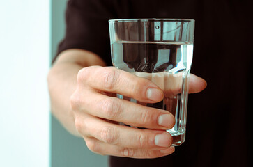 A glass with clean melted water in the hand of a man