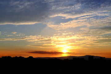 sunset in evening beautiful dramatic sky with cloud, background light sky gradient, concept of heavenly space, abode of God, meditative calmness and greatness, black silhouette of hills at bottom