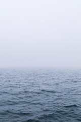 View of waves on the ocean with vanishing horizon on a foggy day. Copy space. Good for natural sea background.