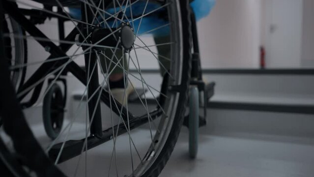 Close-up wheel of wheelchair at stairs indoors with unrecognizable boy. Problem of accessibility and disability in premises