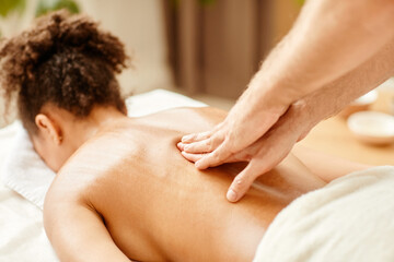 Obraz na płótnie Canvas Close up of male hands massaging back of young African American woman enjoying SPA session