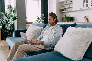 Young concentrated entepreneur working at home on his ;aptop in a beautiful interior.