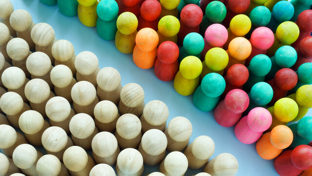 A line of multi-colored figurines and regular ones. Diversity and inclusion.