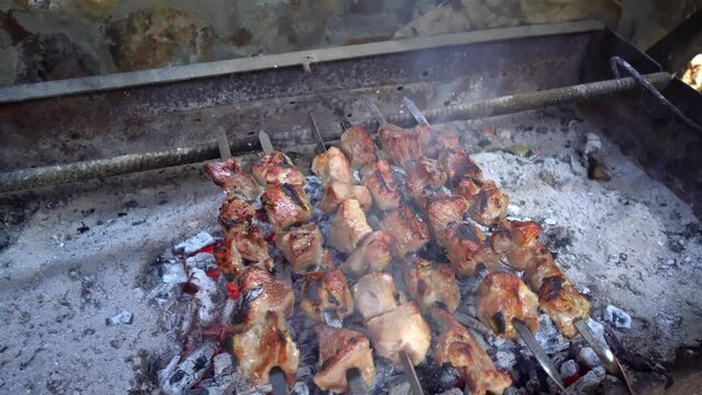 Pickled kebab is cooked on grill on coals. Barbecue is popular in Eastern Europe. Mouth-watering pieces of marinated meat strung on skewers cooked with charcoal grills in fragrant hot smoke. Close-up
