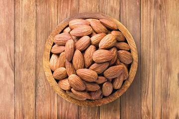 almond nuts peeled roasted in bowl on wooden table background, top view. organic vegetarian food.